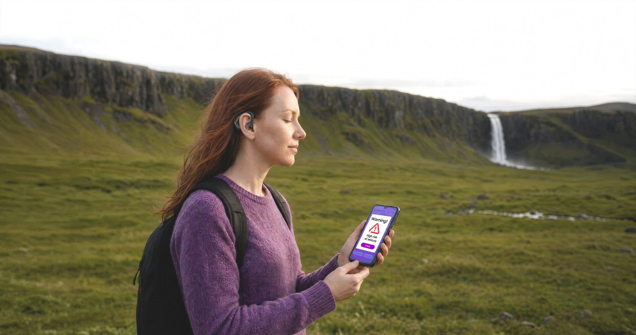 A woman wearing the Episeras earpiece, checking the companion app outdoors